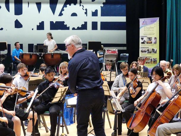 A conductor leads the orchestra on the final show