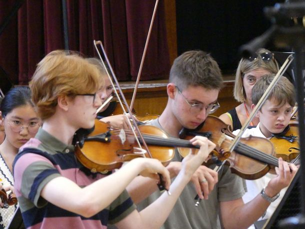 two teenagers playing violins in a group